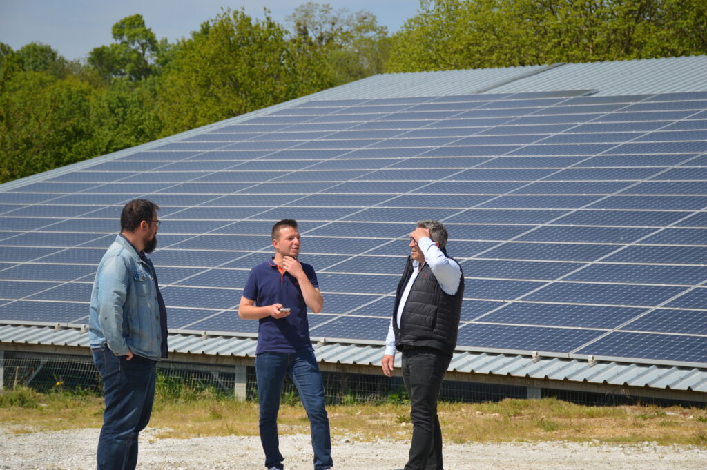 Agriculteur et conseillers devant un panneau solaire